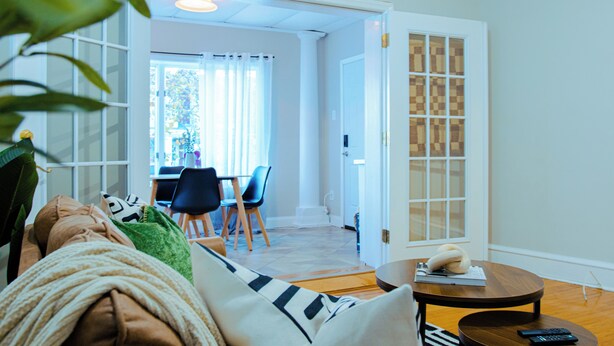 A living room with a sofa, a coffee table, and a dining area with chairs and a table. - Charming 1Br With French Door Home Theater Screen & Rain Shower (Philadelphia)