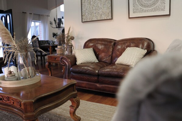 A living room with a brown leather sofa, a wooden coffee table, and a patterned rug. - Villa de La Rosa en Valle de Gpe  (Valle de Guadalupe)