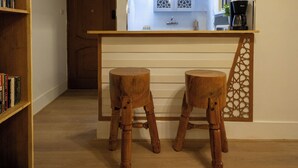 A kitchen with wooden stools, a bookshelf, and a door leading to another room.