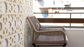 A wicker chair on a balcony with a patterned wall and wooden floor.