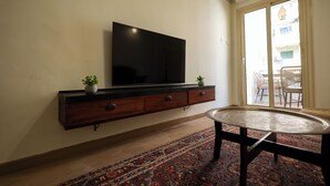 A living room with a flat-screen TV mounted on a wooden cabinet, a patterned rug, and a round coffee table.