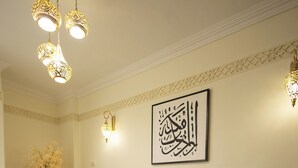 A living room with a green sofa, a patterned rug, and a wall-mounted artwork.