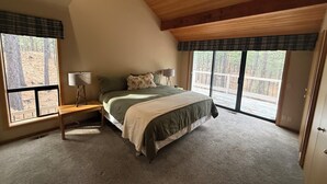 A bedroom with a bed, a nightstand, a lamp, and large windows. - 3-bedroom house in brilliant Black Butte ranch with cozy living spaces (Sisters)