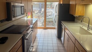 A modern kitchen with wooden cabinets, a built-in oven, a microwave, a refrigerator, and a sink. - 3-bedroom house in brilliant Black Butte ranch with cozy living spaces (Sisters)