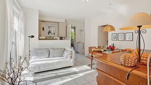 Ein modernes Wohnzimmer mit einer Couch, einem Essbereich mit Tisch und einer Küche im Hintergrund.