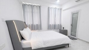 Une chambre à coucher moderne avec un lit, des rideaux, une table de chevet et une porte.