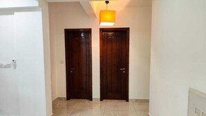 Un couloir avec deux portes en bois, un luminaire au plafond et un sol carrelé.