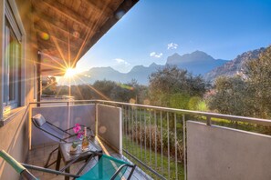 A balcony with a table and chairs, overlooking a mountainous landscape. - Agritur Laura - L'angolo dei Fiori 4 with Shared Garden, Torbole sul Garda, Italy (Torbole sul Garda)