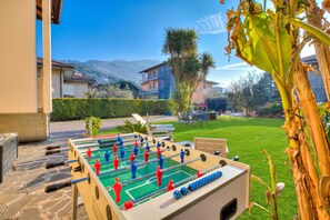 An outdoor foosball table with a clear view of a residential area, including houses and a mountain in the background. - Agritur Laura - L'angolo dei Fiori 4 with Shared Garden, Torbole sul Garda, Italy (Torbole sul Garda)