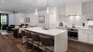 Een moderne keuken met een centraal eiland, barkrukken en een zithoek met een bank en stoelen.