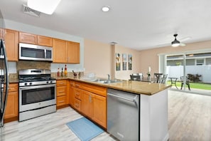 A modern kitchen with wooden cabinets, stainless steel appliances, and a large island with a sink.