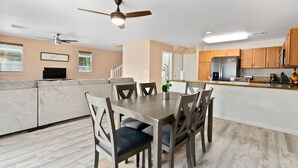 Een moderne keuken met houten kastjes, een centraal eiland en een eethoek met een tafel en stoelen.