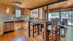 Un intérieur en bois comprenant une cuisine, un coin repas et de grandes fenêtres.