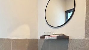 Ein Badezimmer mit Toilette, Mülleimer und Spiegel an der Wand.