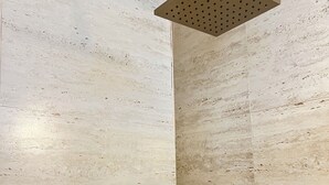 Un pommeau de douche fixé sur un mur à texture.