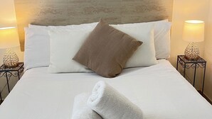 Un lit bien fait, avec une serviette enroulée, des oreillers blancs, un oreiller marron et une tête de lit en bois.