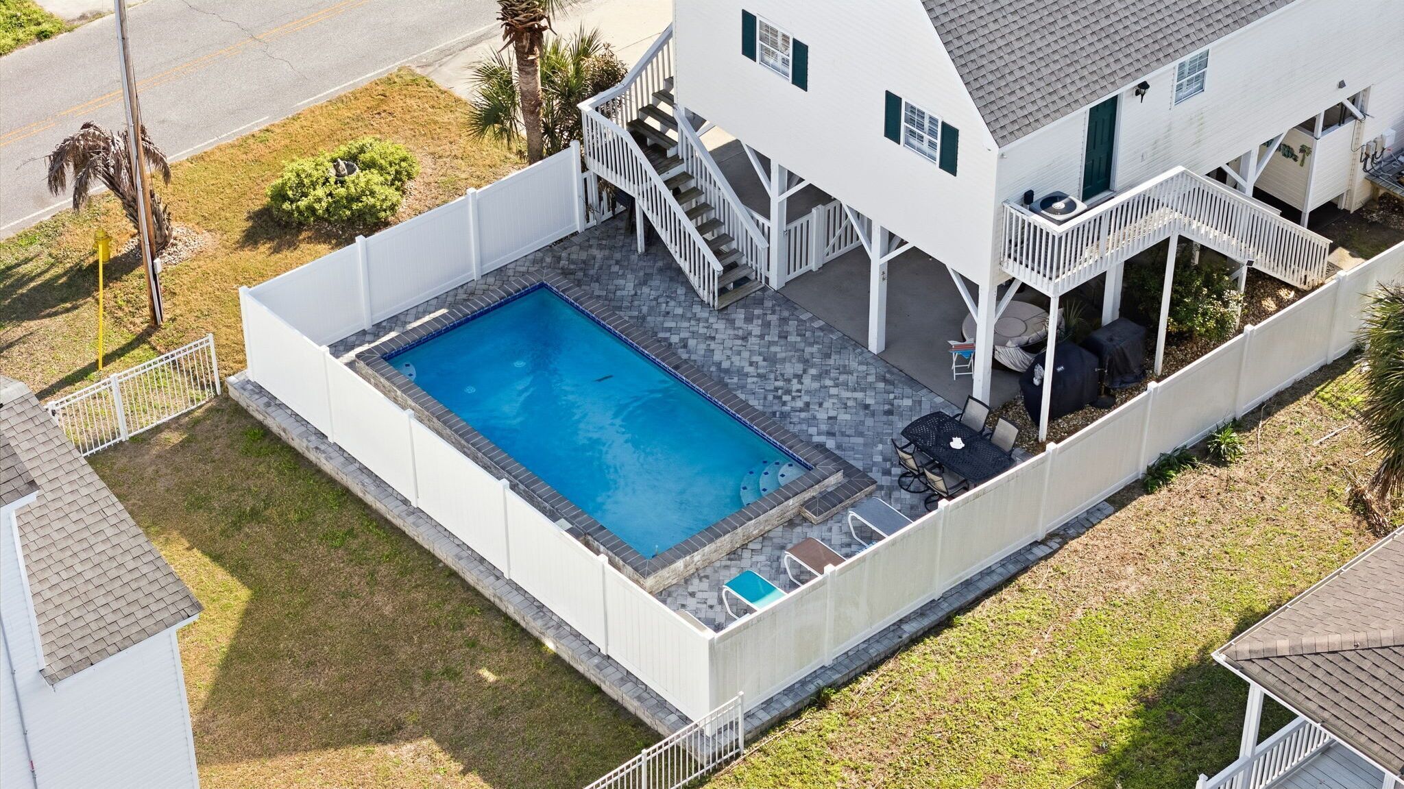 Ett hus med en swimmingpool, en täckt uteplats och en inhägnad trädgård.