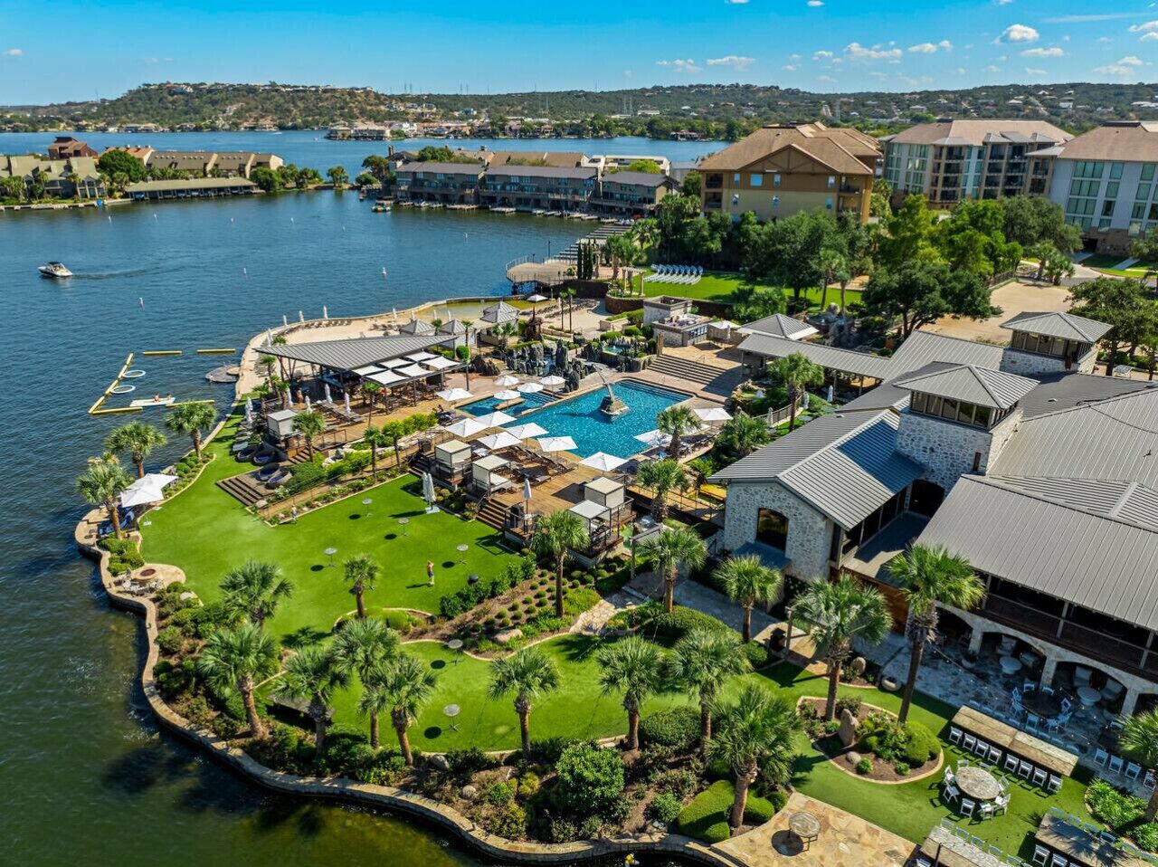 Vista aérea de un resort con una piscina grande, varios edificios y un puerto deportivo.