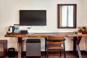 A hotel room with a desk, chair, television, and a small refrigerator. - RS1 Hotel (Vientiane)