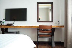 A hotel room with a bed, a desk with a flat-screen TV, a chair, a mirror, and a window with curtains. - RS1 Hotel (Vientiane)