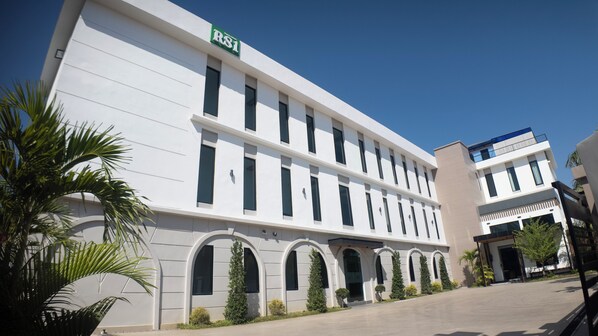 A modern building with a sign reading 'RSI' on the top. It has multiple windows and a flat roof. - RS1 Hotel (Vientiane)