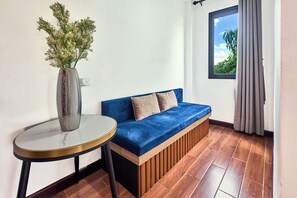 Una habitación con un sofá azul, una mesa redonda y un florero con flores.