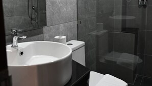 A modern bathroom with a large sink, toilet, and glass-enclosed shower. - RS1 Hotel (Vientiane)