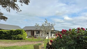 A house with a covered patio, a lawn, and a garden with flowers.