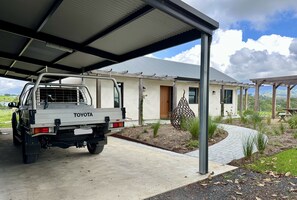 Uma caminhonete Toyota estacionada sob uma cobertura, com uma casa ao fundo.