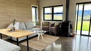 A living room with a sofa, a coffee table, a fireplace, and large windows with a view.