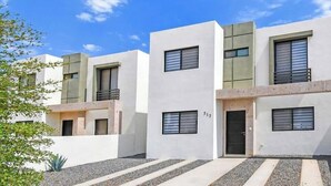 A modern multi-story residential building with a clean, minimalist design, featuring a central entrance and uniform window patterns.