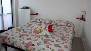Una camera da letto con un letto, un comodino, una lampada, un termosifone e una finestra.