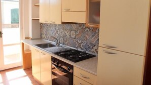 A kitchen with light-colored cabinets, a patterned backsplash, a gas stove, and a sink. - Four-room apartment 30 meters from the sea, with parking space (Marcelli)