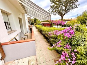 Il s’agit d’une propriété résidentielle dotée d’un espace extérieur aménagé et abrité, d’un jardin avec des plantes à fleurs et d’un grand arbre.