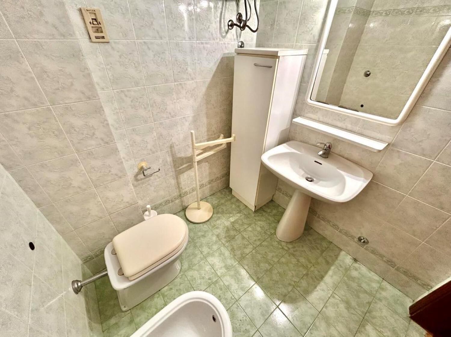 Une salle de bain équipée de toilettes, d’un bidet, d’un lavabo et d’un miroir.