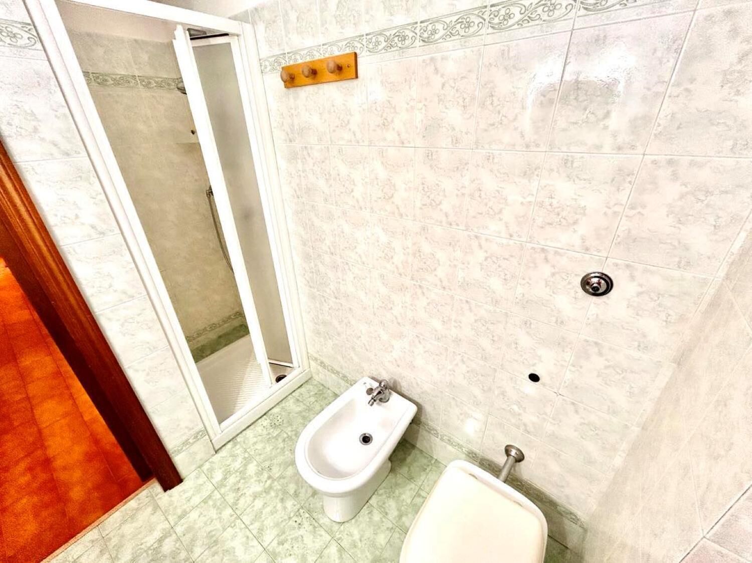 A bathroom with a bidet, a toilet, and a shower area.