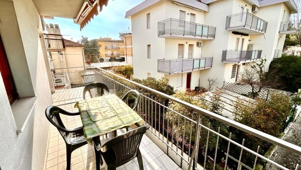 Un balcón con mesa y sillas, con vistas a una zona residencial con varios edificios.