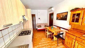 Una cocina compacta con estufa a gas, armarios de madera y un comedor con mesa y sillas.