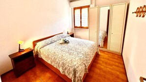Un dormitorio con una cama, una mesita de noche, un ventanal y un armario.