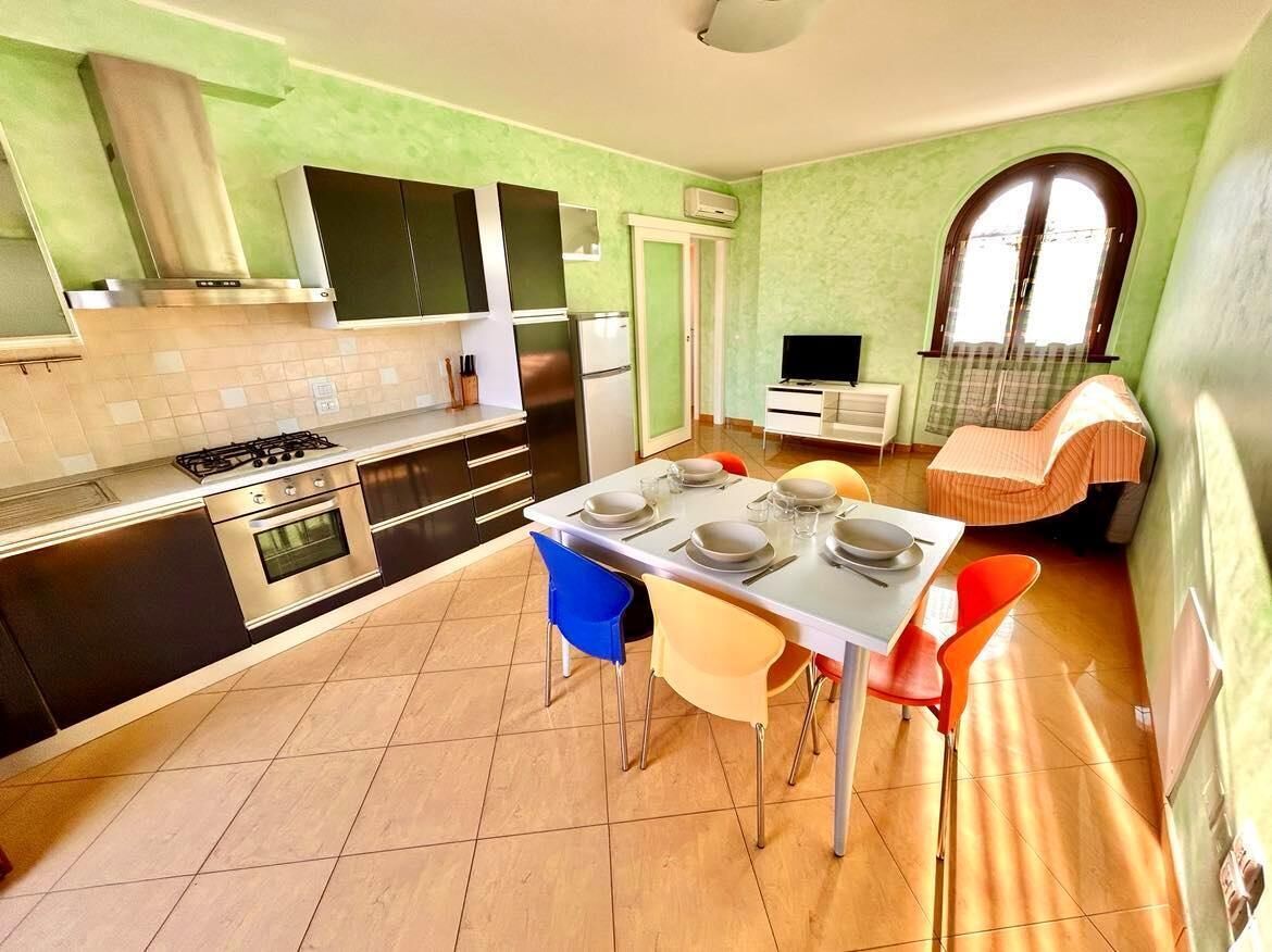Eine kompakte Küche mit modernen Geräten, ein Essbereich mit Stühlen und eine kleine Sitzecke mit einer Couch.