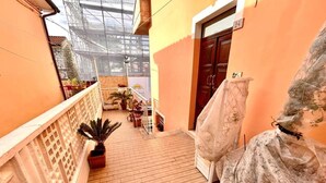 A corridor with a wooden floor, potted plants, a covered bench, and a door marked with the number 24. - Brand new one-bedroom apartment in downtown with 2 bathrooms and WI-FI (Numana)