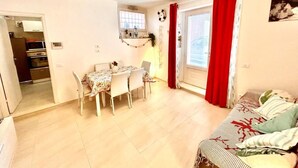 A compact living space with a dining area, a sofa, and a window with red curtains. - Brand new one-bedroom apartment in downtown with 2 bathrooms and WI-FI (Numana)
