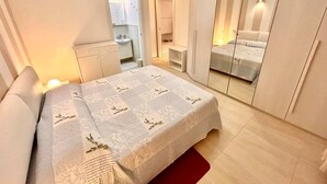 A bedroom with a bed, a mirror, a wardrobe, and a small bathroom. - Brand new one-bedroom apartment in downtown with 2 bathrooms and WI-FI (Numana)