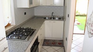 Een compacte keuken met witte kastjes, een gasfornuis en een spoelbak.