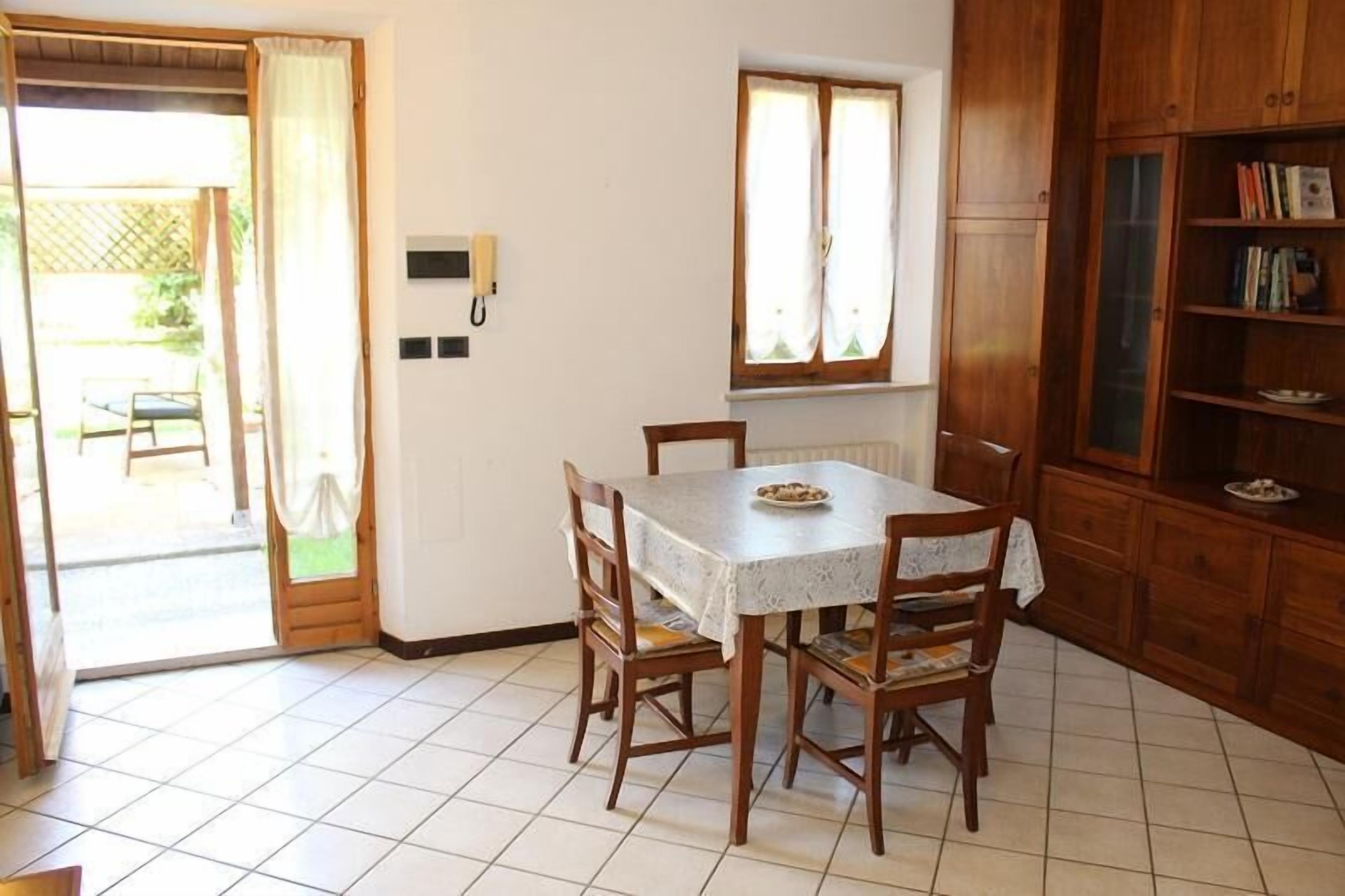 Un coin repas comprenant une table, des chaises, une fenêtre et un meuble en bois contenant des livres.