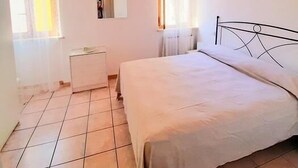 Een slaapkamer met een bed, nachtkastje, radiator en raam.