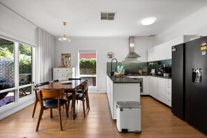 Une cuisine moderne avec un coin repas, de grandes fenêtres et une vue sur la verdure.