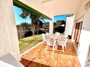 A patio with a table and chairs, a view of the surrounding landscape, and a building with a white exterior.