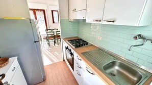 Cozinha com armários brancos, fogão a gás, pia e geladeira.