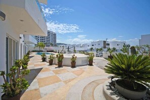 A rooftop terrace with a pool, potted plants, and modern buildings in the background. - Oceanview Balcony, BBQ Lounge, Near Malecon (La Paz)